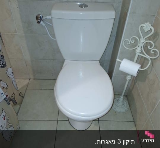 אסלה לבנה עם מיכל הדחה בחדר אמבטיה